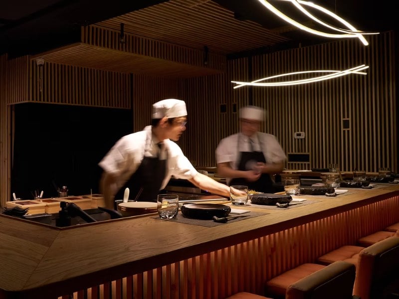 A sushi bar with chefs preparing food and seating for customers.