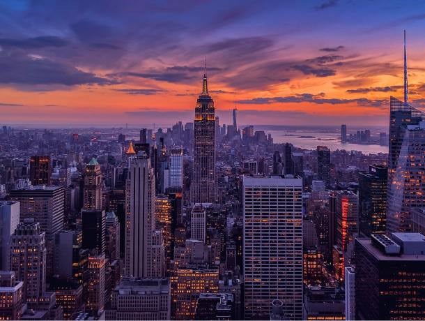A cityscape at sunset with many skyscrapers and a vibrant sky.